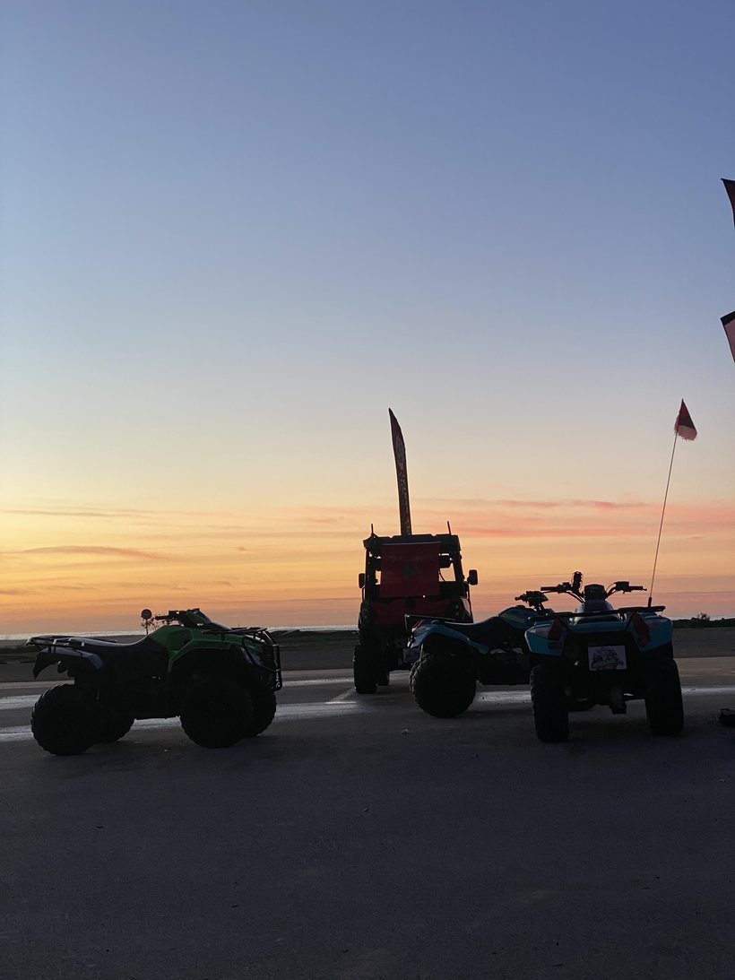 Quads et buggy alignés sur la plage au coucher du soleil, drapeau marocain